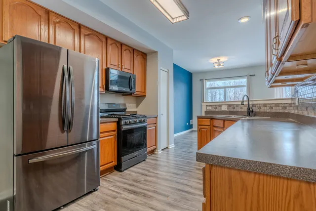 a kitchen with stainless steel appliances granite countertop a refrigerator a stove a sink a microwave and island