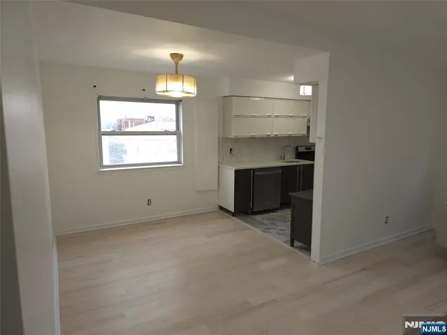 an empty room with chandelier fan and windows