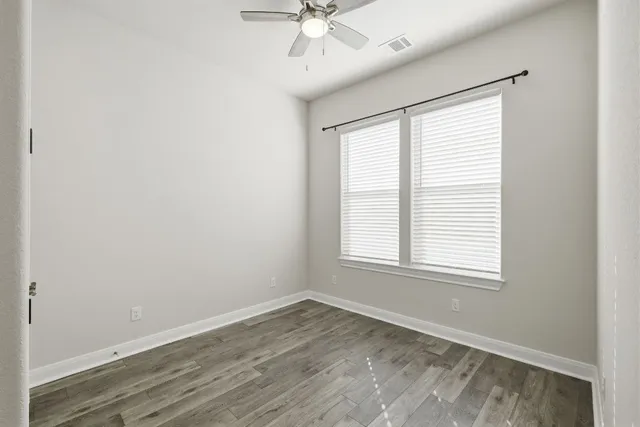an empty room with a window and a fan