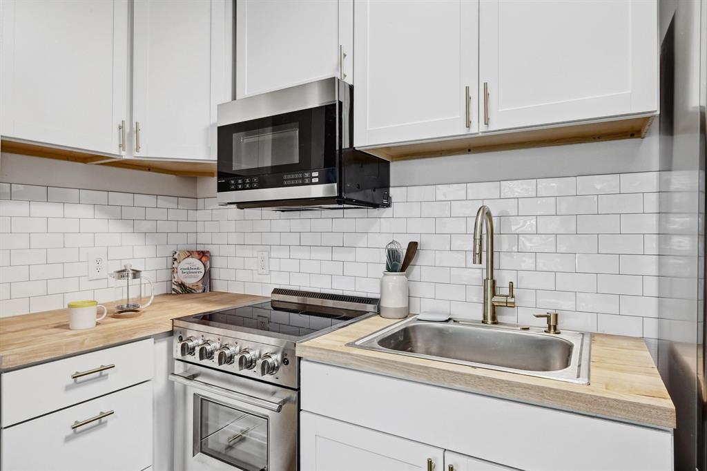 2802 Whitis Avenue, Unit 106 Austin, TX 78705 - Photo 6 of 8 Kitchen featuring white shaker-style cabinetry, wood-finish countertops, subway tile backsplash, stainless steel appliances, and a gooseneck faucet