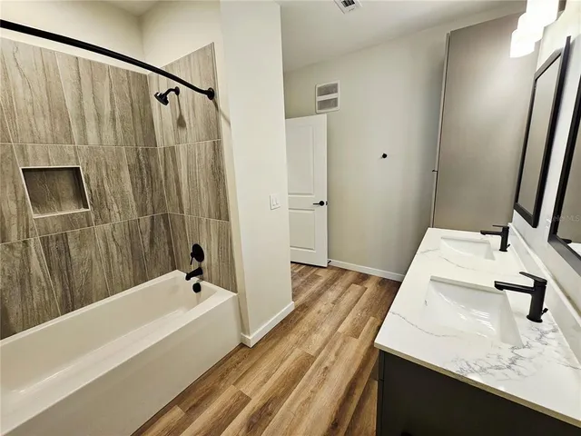 a bathroom with a granite countertop sink a mirror and a bathtub