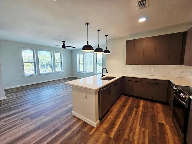 a kitchen with stainless steel appliances granite countertop a sink a stove and a wooden floors