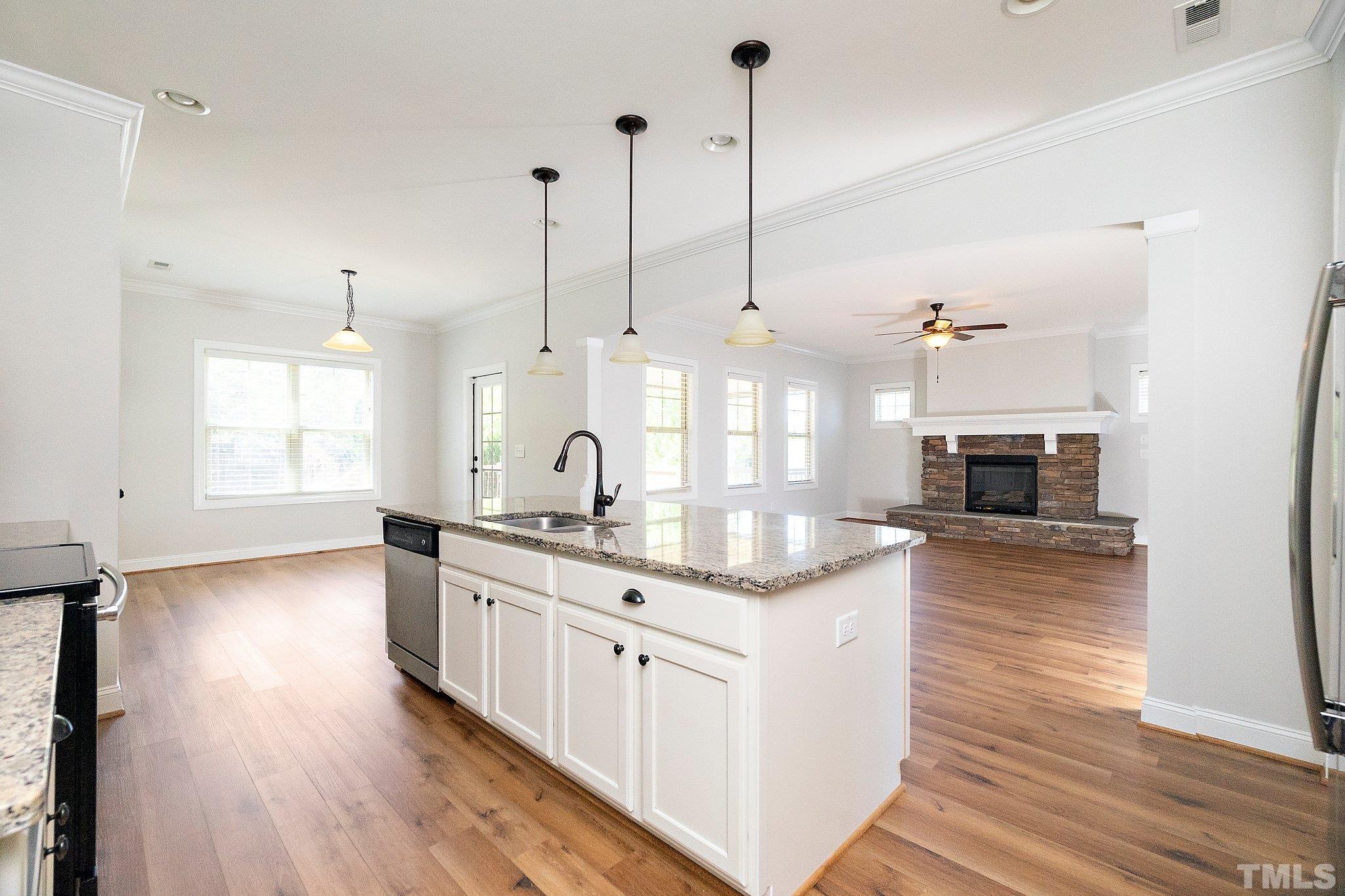 4401 Glengrove Road Raleigh, NC 27616 - Photo 12 of 26 a kitchen with stainless steel appliances kitchen island granite countertop a stove a sink a center island and a wooden floor