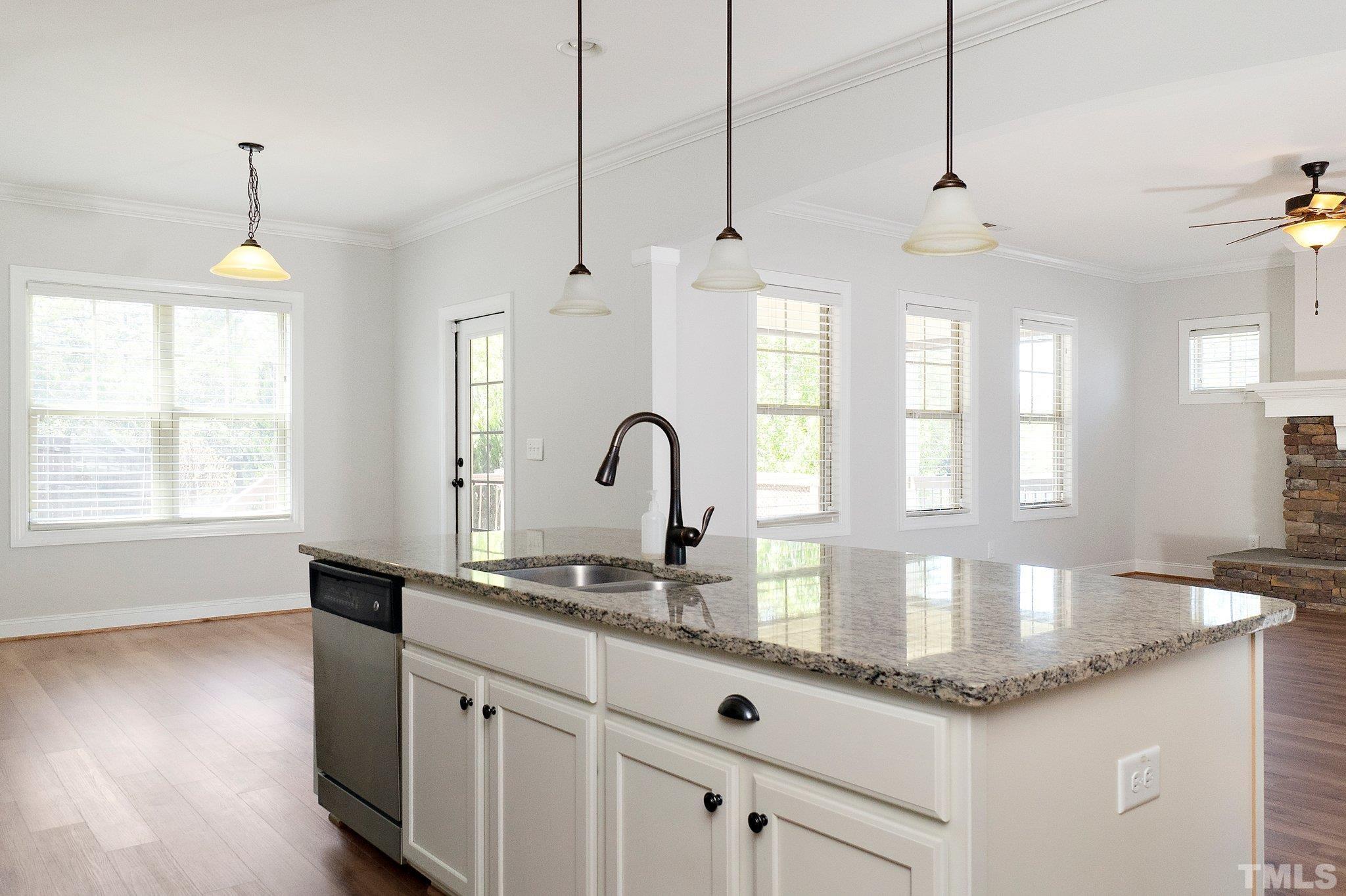 4401 Glengrove Road Raleigh, NC 27616 - Photo 15 of 26 a kitchen with granite countertop a stove a sink a chandelier and wooden floor