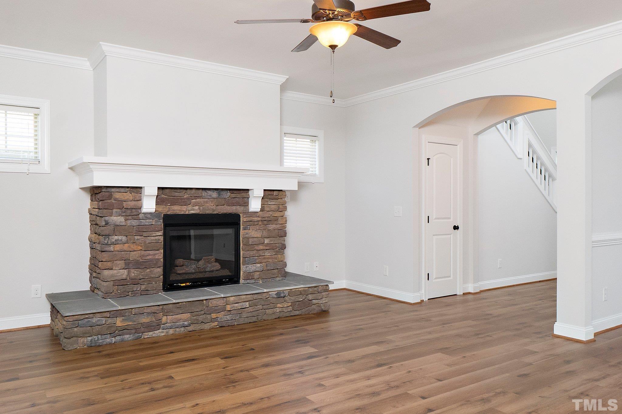 4401 Glengrove Road Raleigh, NC 27616 - Photo 17 of 26 an empty room with wooden floor a ceiling fan a fireplace and windows