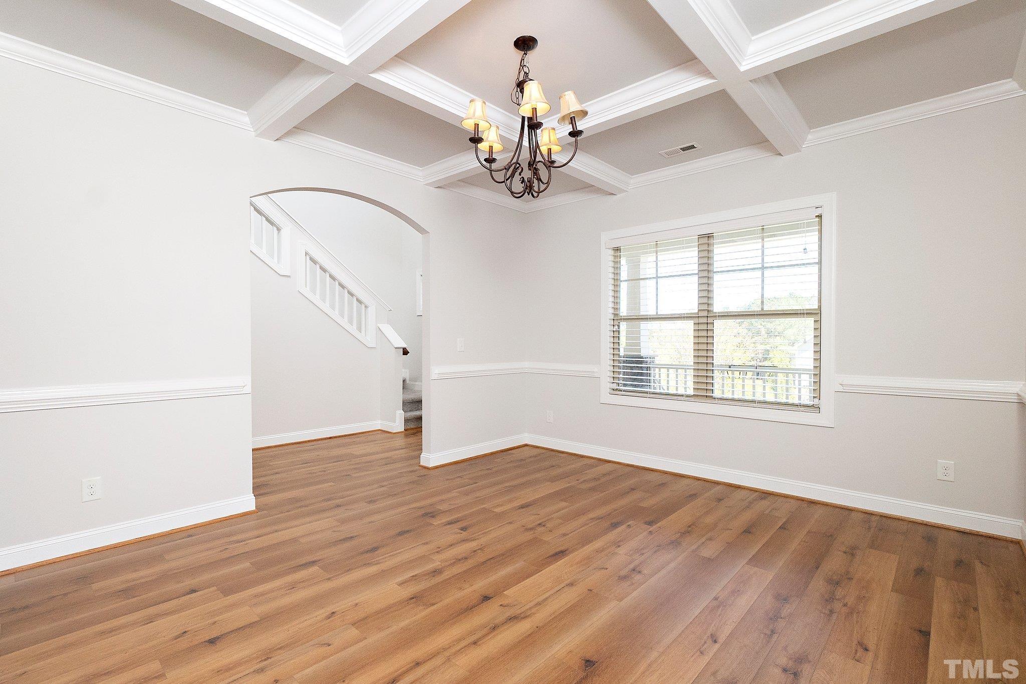 4401 Glengrove Road Raleigh, NC 27616 - Photo 7 of 26 an empty room with wooden floor chandelier and windows