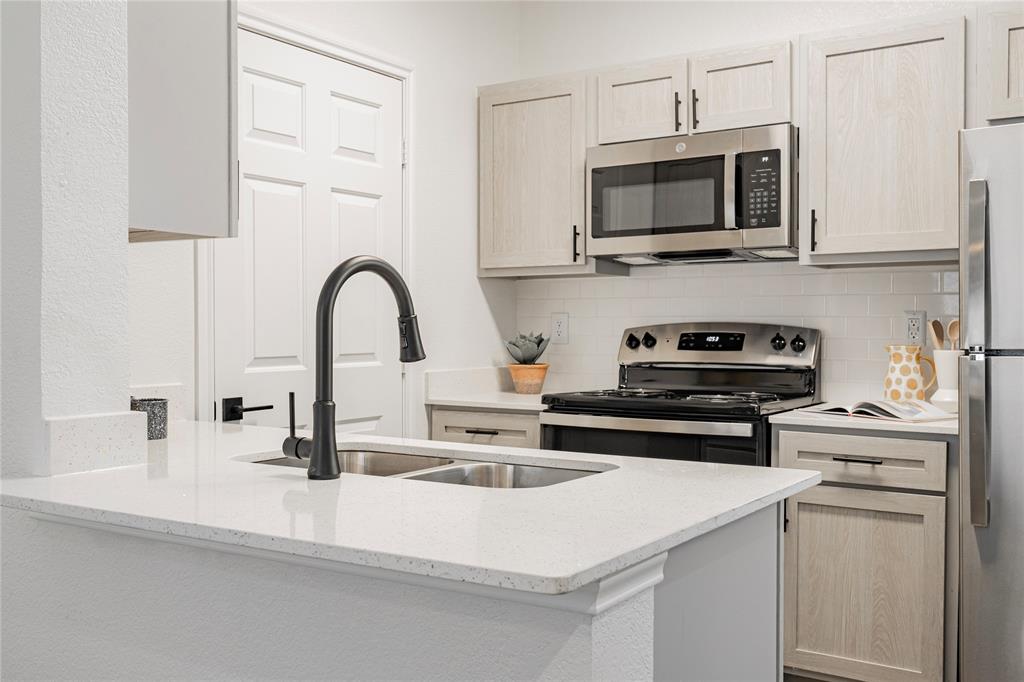 1600 North 9th Street, Unit A1R Midlothian, TX 76065 - Photo 7 of 15 a kitchen with stainless steel appliances a stove a sink and a microwave