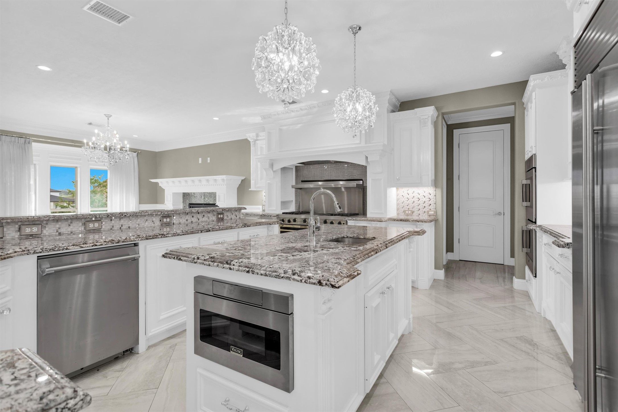 10887 Decatur Street Willis, TX 77318 - Photo 14 of 50 A chef’s kitchen built to impress — oversized island with prep sink, granite countertops, custom cabinetry, and high-end Viking appliances. Open sightlines keep everything connected while still giving you plenty of workspace.
