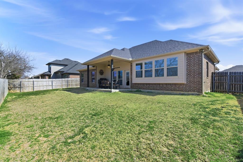 711 Hadley Lane Valley View, TX 76272 - Photo 30 of 40 Rear view of house with ceiling fan, brick siding, a fenced backyard, a patio area, and roof with shingles