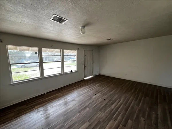 an empty room with wooden floor and windows