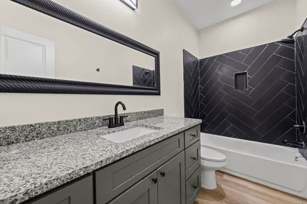 a bathroom with a granite countertop sink a toilet and bathtub