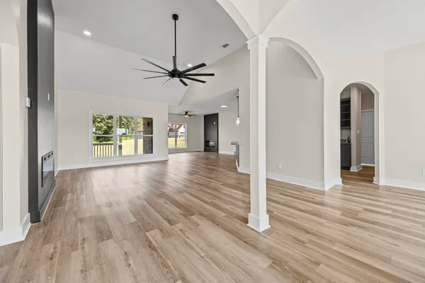 a view of an empty room with a window and wooden floor