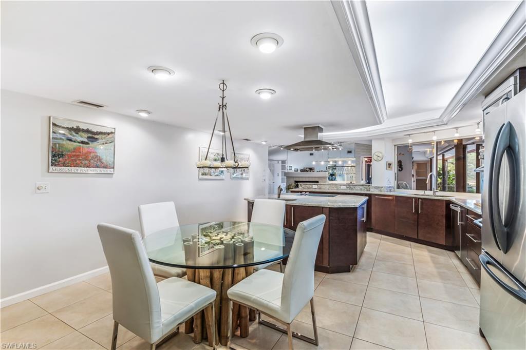 550 Bald Eagle Drive Naples, FL 34105 - Photo 12 of 37 a kitchen with stainless steel appliances kitchen island granite countertop a table chairs and a refrigerator