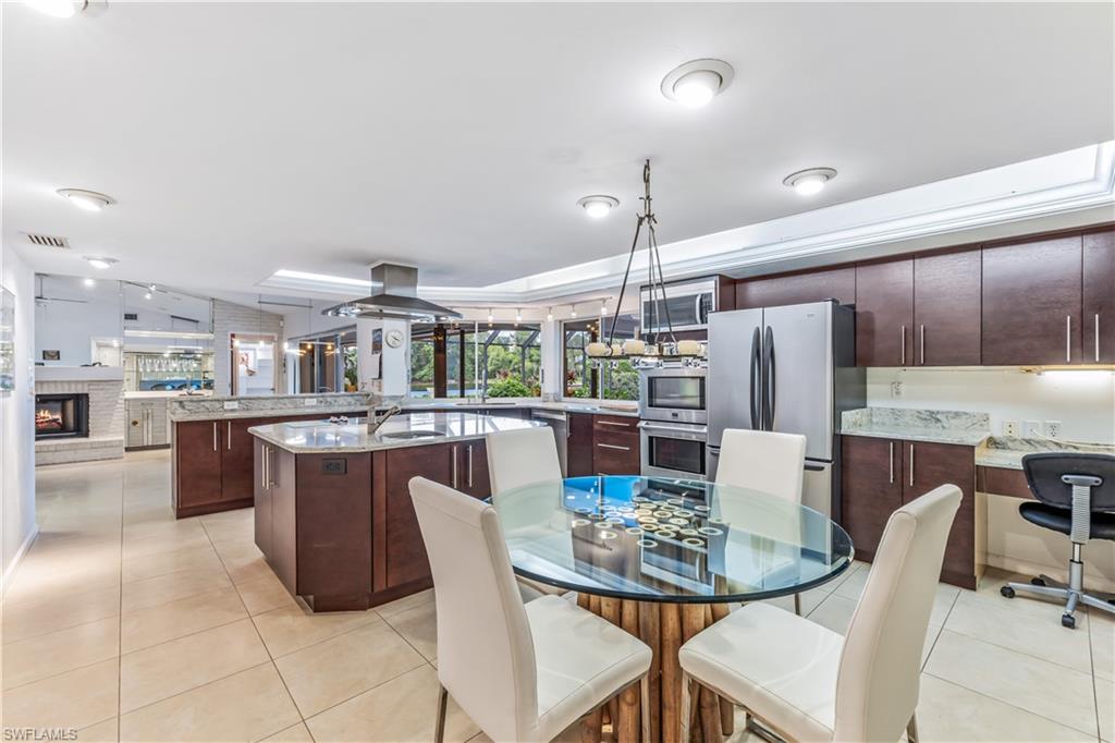 550 Bald Eagle Drive Naples, FL 34105 - Photo 13 of 37 a dining room with stainless steel appliances kitchen island granite countertop a dining table and chairs