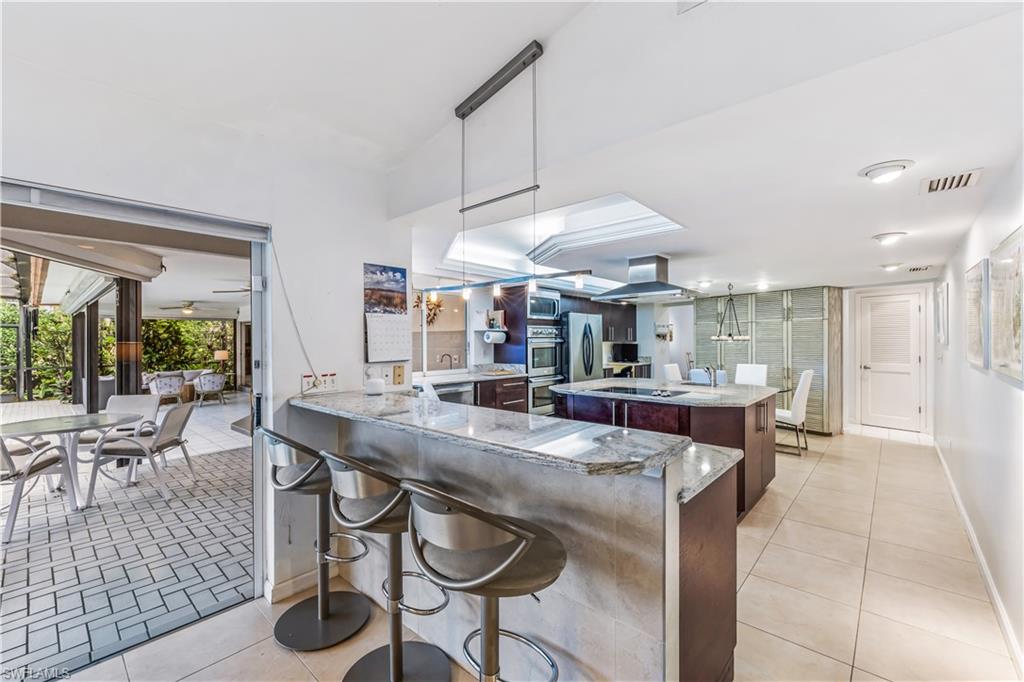 550 Bald Eagle Drive Naples, FL 34105 - Photo 14 of 37 a dining hall with stainless steel appliances kitchen island granite countertop a table and chairs