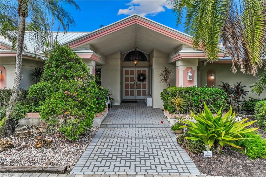 550 Bald Eagle Drive Naples, FL 34105 - Photo 2 of 37 a view of a brick house with plants and a large tree