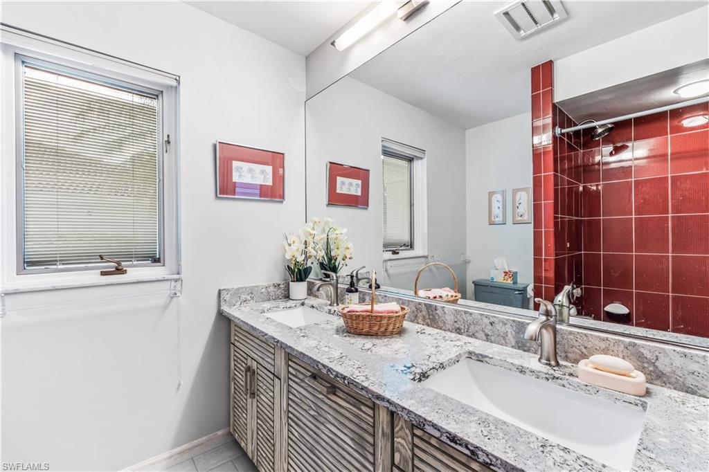 550 Bald Eagle Drive Naples, FL 34105 - Photo 25 of 37 a bathroom with a granite countertop sink a mirror and a shower