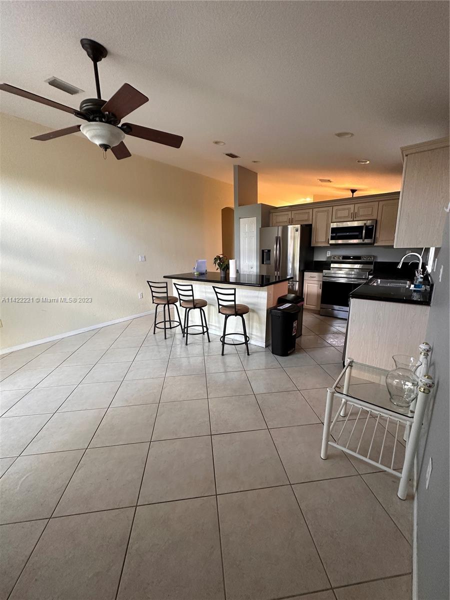 1041 Southeast 20th Road Homestead, FL 33035 - Photo 15 of 40 a group of chairs sitting in kitchen and a refrigerator