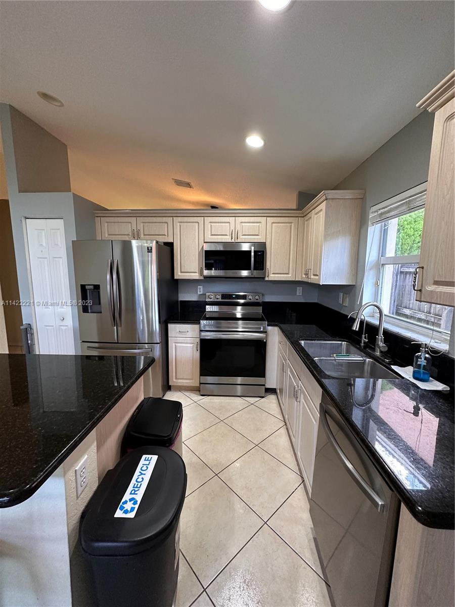 1041 Southeast 20th Road Homestead, FL 33035 - Photo 19 of 40 a kitchen with stainless steel appliances granite countertop a sink a stove top oven a counter space and cabinets