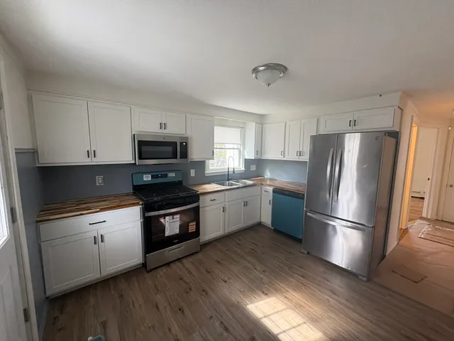 a kitchen with granite countertop stainless steel appliances and wooden floor