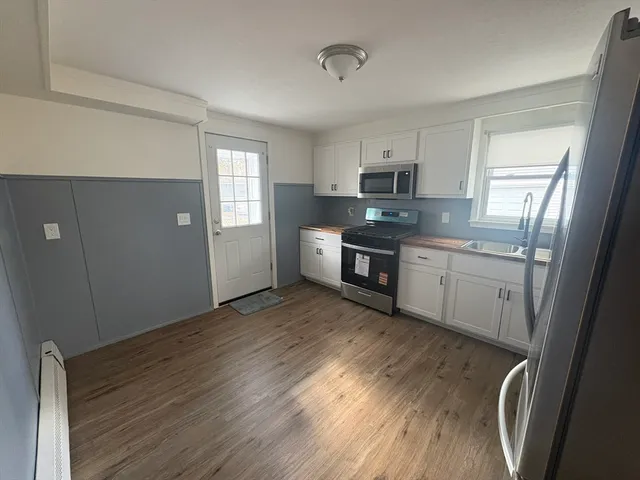 a kitchen with stainless steel appliances granite countertop a refrigerator a sink dishwasher a stove top oven a refrigerator with wooden floor and cabinets