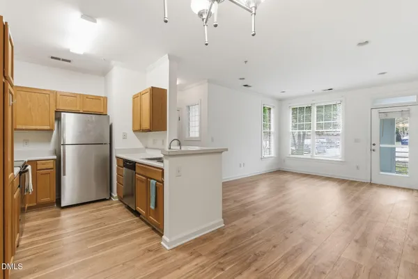 a kitchen with stainless steel appliances granite countertop a refrigerator a stove a sink dishwasher and a refrigerator with wooden floor