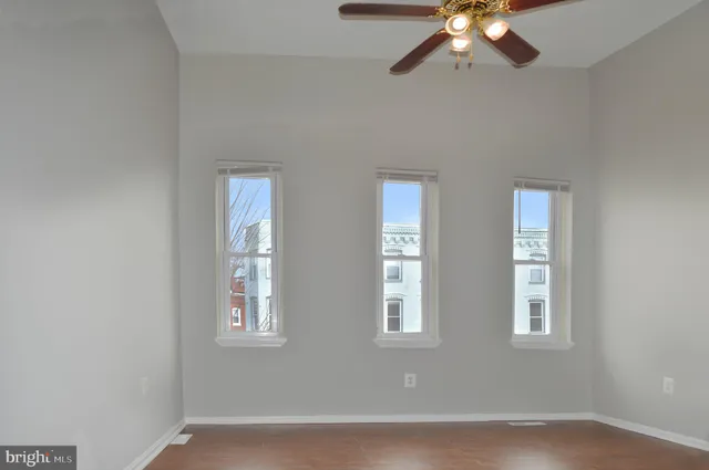 an empty room with windows and fan