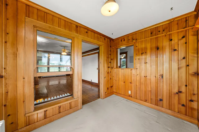 a view of an empty room with wooden floor fireplace and a window