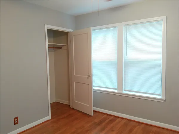 a view of an empty room with wooden floor and closet