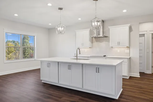 a kitchen with cabinets a sink dishwasher a stove and a dining table with wooden floor