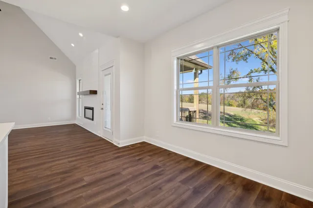 an empty room with wooden floor fan and windows
