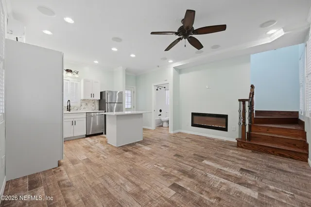 a view of kitchen and empty room with wooden floor