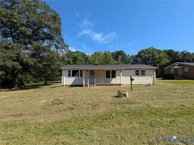 a front view of house with yard and trees in the background