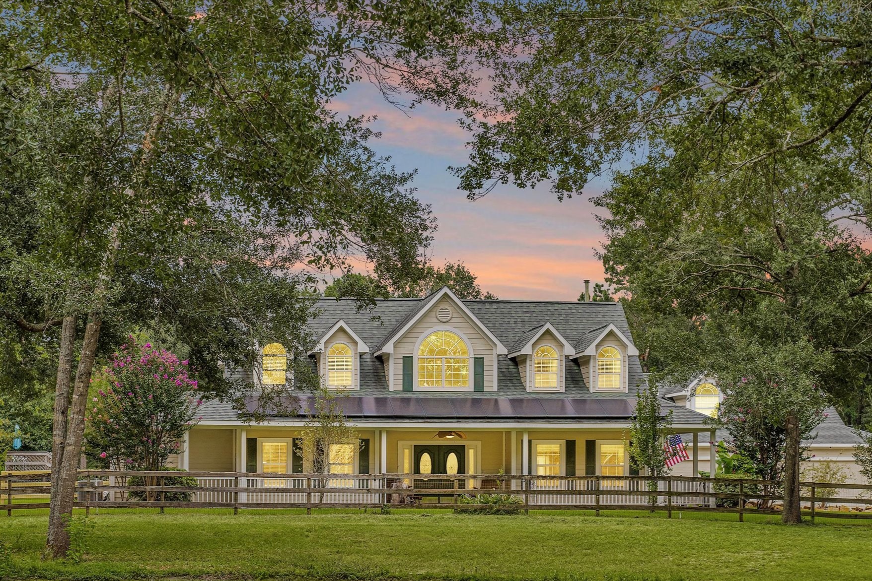 a front view of a house with a garden and trees