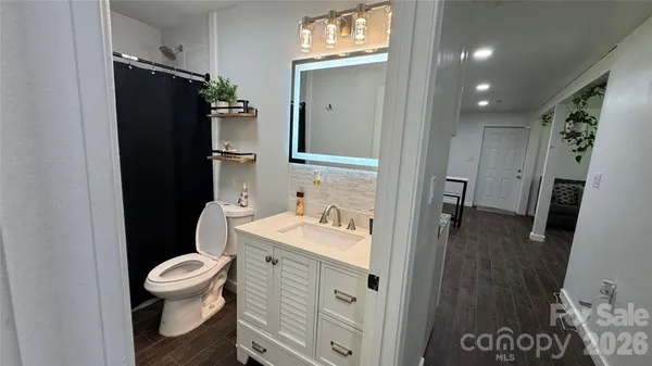 a bathroom with a sink a toilet a mirror and shower