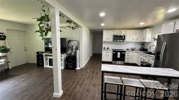 a kitchen with stainless steel appliances granite countertop a refrigerator a stove top oven a sink dishwasher and white cabinets with wooden floor