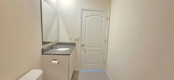 a bathroom with a granite countertop sink toilet and mirror
