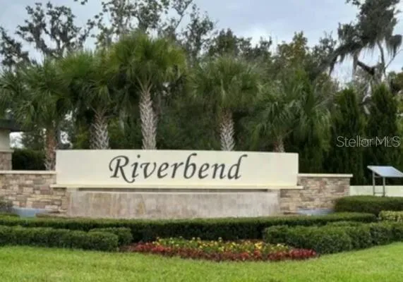 a view of sign board with yard and trees