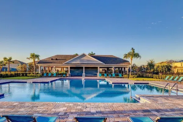 a front view of a house with swimming pool lawn chairs and lake view