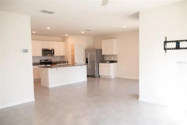 a view of kitchen with stainless steel appliances kitchen island granite countertop a stove a sink a refrigerator and white cabinets with wooden floor