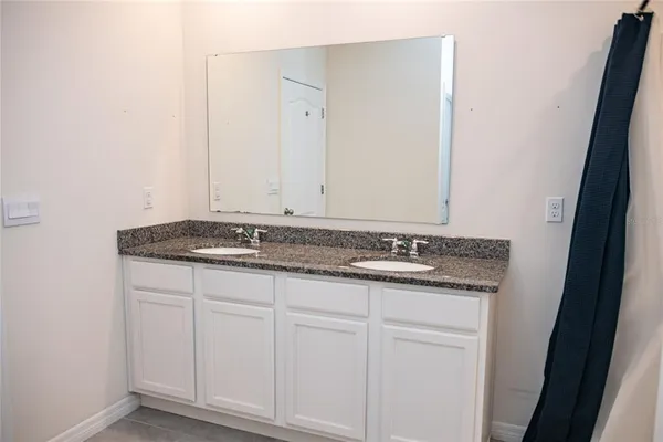 a bathroom with a granite countertop sink and white cabinets