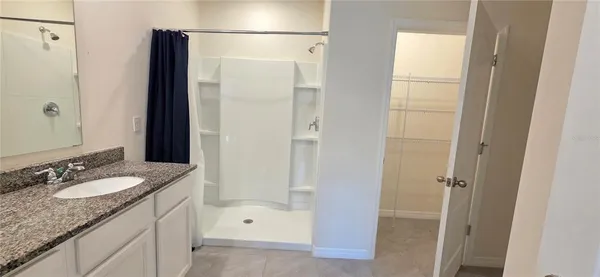 a bathroom with a granite countertop shower sink vanity and mirror
