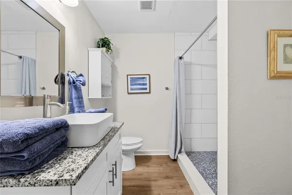 a bathroom with a granite countertop sink a toilet a mirror and shower