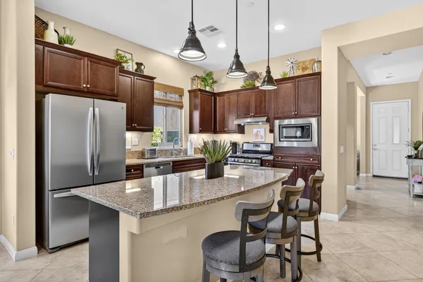 a kitchen with stainless steel appliances kitchen island granite countertop a table chairs and a refrigerator