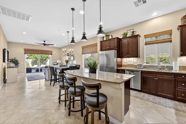a kitchen with stainless steel appliances granite countertop table chairs sink and cabinets