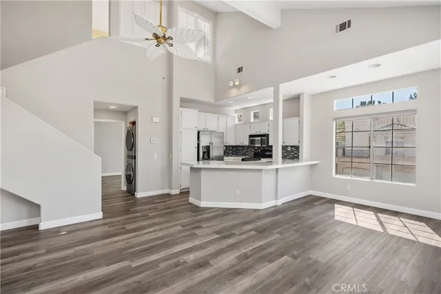a kitchen with a refrigerator and white cabinets with wooden floor