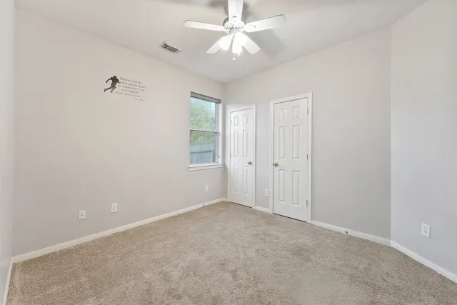 an empty room with a ceiling fan and a window