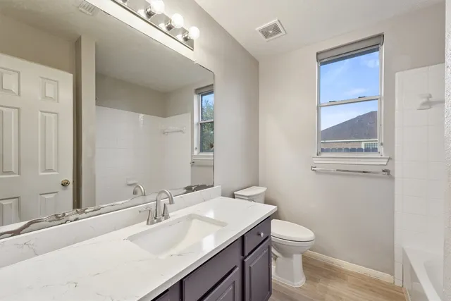 a bathroom with a granite countertop sink a toilet and a mirror