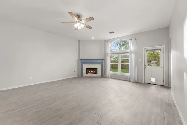 a view of an empty room with a window and wooden floor