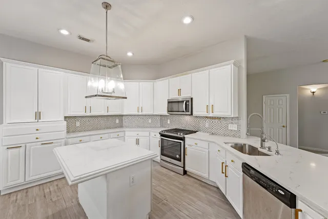 a kitchen with a sink a stove a refrigerator and white cabinets